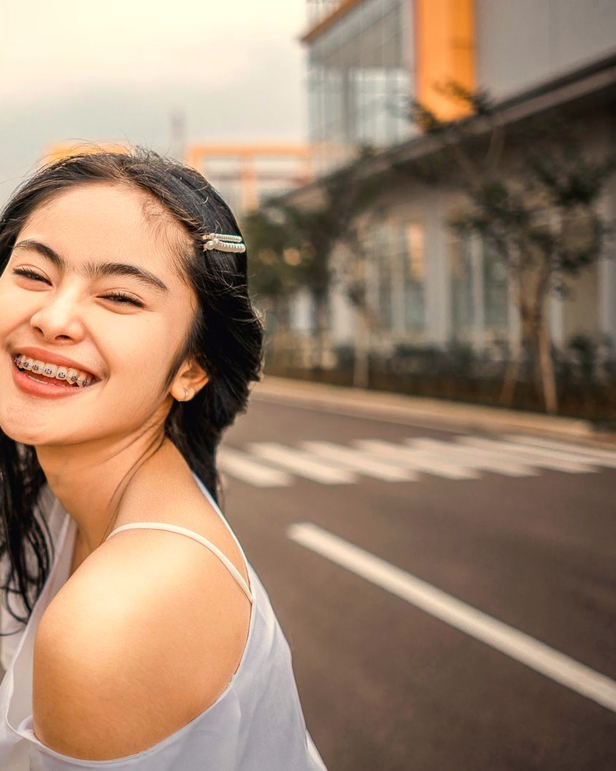 A teenager with braces laughing in warm sunlight.